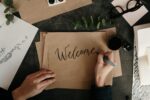Eine Hand die Welcome auf ein Papier schreibt